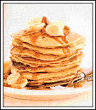 stack of pancakes with butter, dripping with maple syrup
